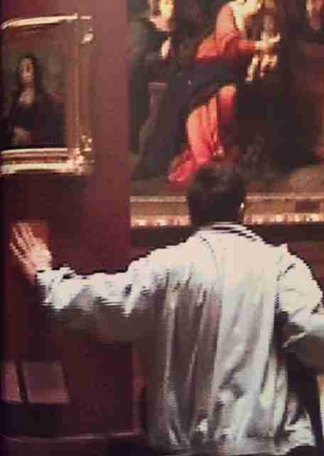 Image of Banksy from behind at the Louvre Museum, 2004 leaving the Mona Lisa with a smile.
