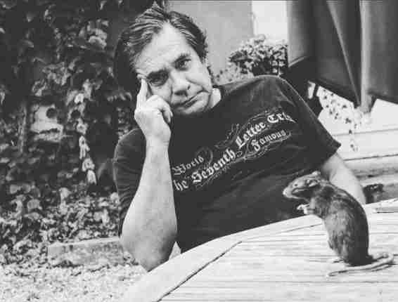 Image of Blek Le Rat, whose name is Xavier Prou, sitting next to a table with a stuffed rat.