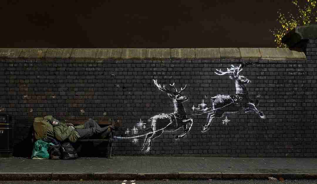 God Bless Birmingham, Banksy. Mural made next to a bench with two reindeer flying.