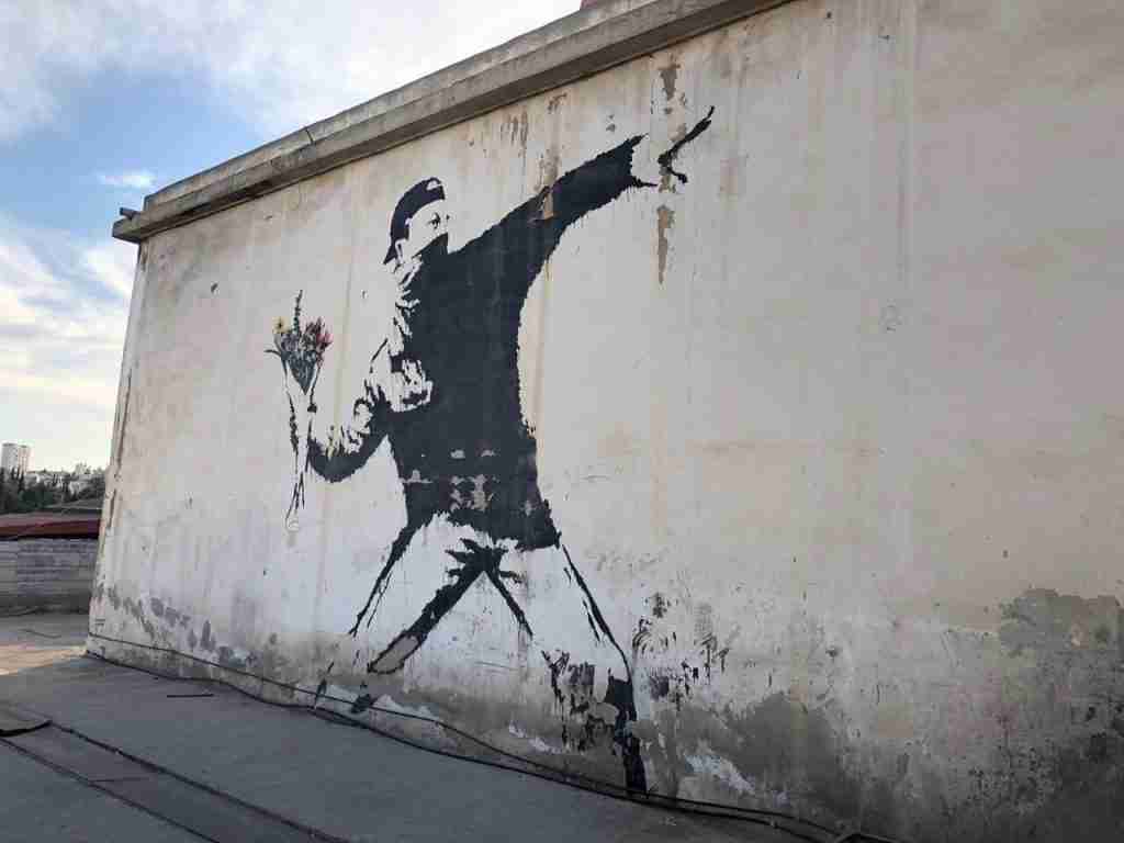 Love is in the air, Flower thrower, Banksy's 2005 work in Jerusalem, shows a protester hiding his face with a scarf and throwing a bouquet of flowers.
