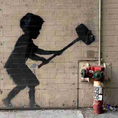 Boy with hammer, Banksy. Black silhouette of a boy with a large sledgehammer threatening to hit an existing red hydrant.