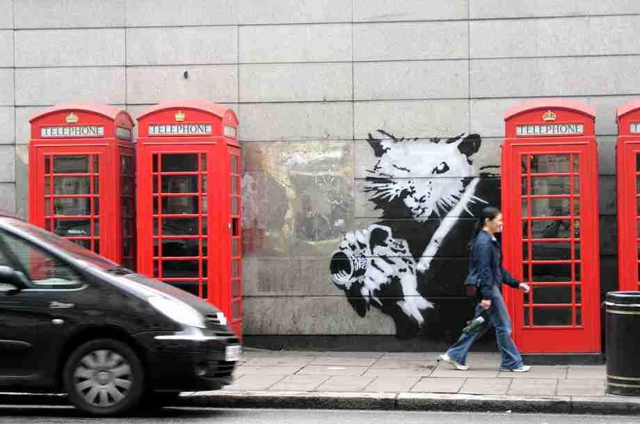 Photographer Rat, Banksy. Image of a rat behind a London telephone booth with a camera.