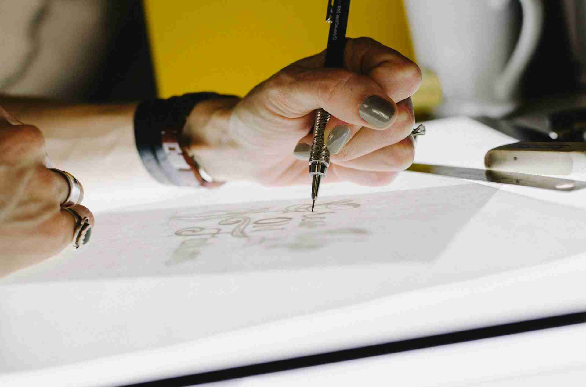 designer-in-accion-kelly-sikkema-o2TRWThve_I-unsplash-1920x1280px.jpg Designer working on a backlit stencil with a mechanical pencil.