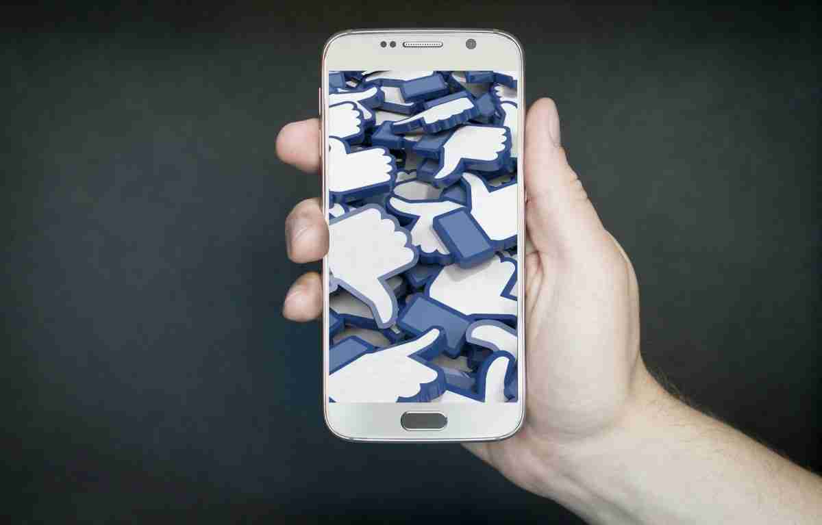 Imagen de la interactividad de un joven con un móvil en la mano y en la pantalla varios iconos de pulgar arriba.