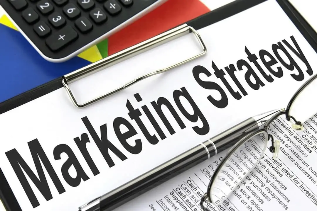 Estrategia de marketing, caartel indicador con las palabras en inglés Marketing Strategy, calculadora y carpeta de informes.